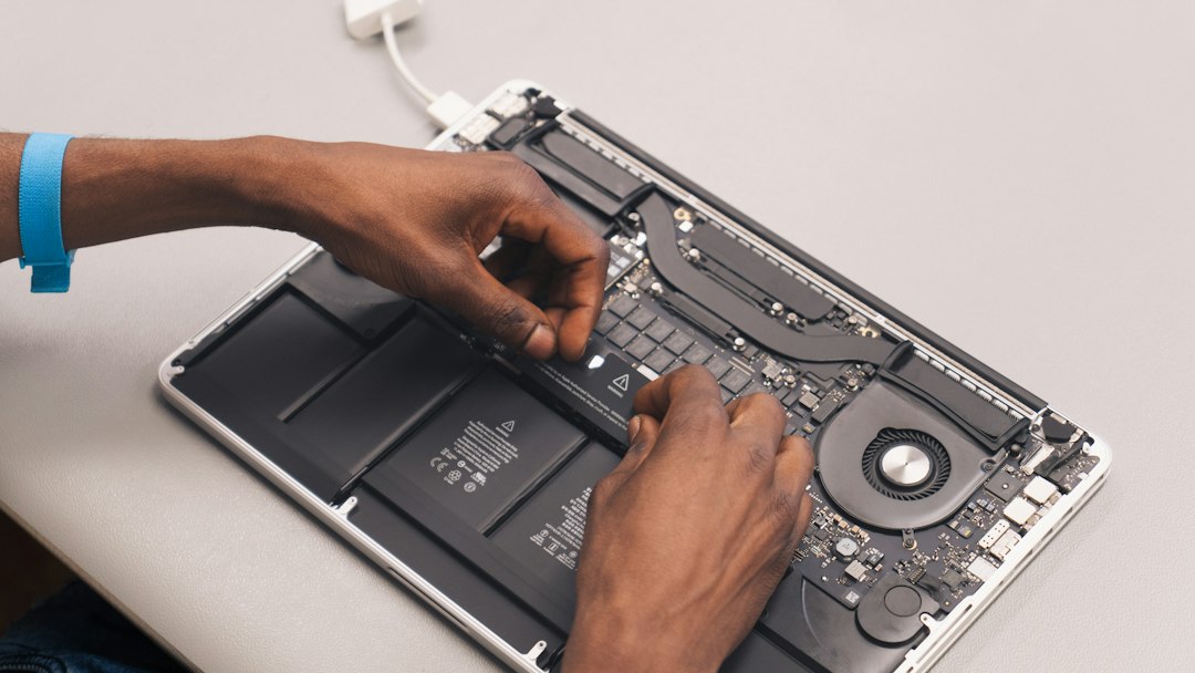 A laptop opened on a repair bench with tools alongside